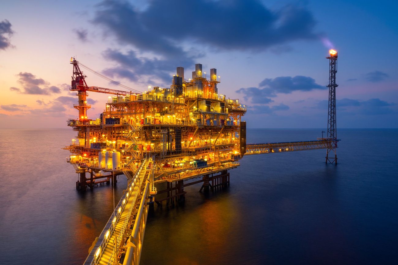 Offshore oil and gas platform lit up at dusk