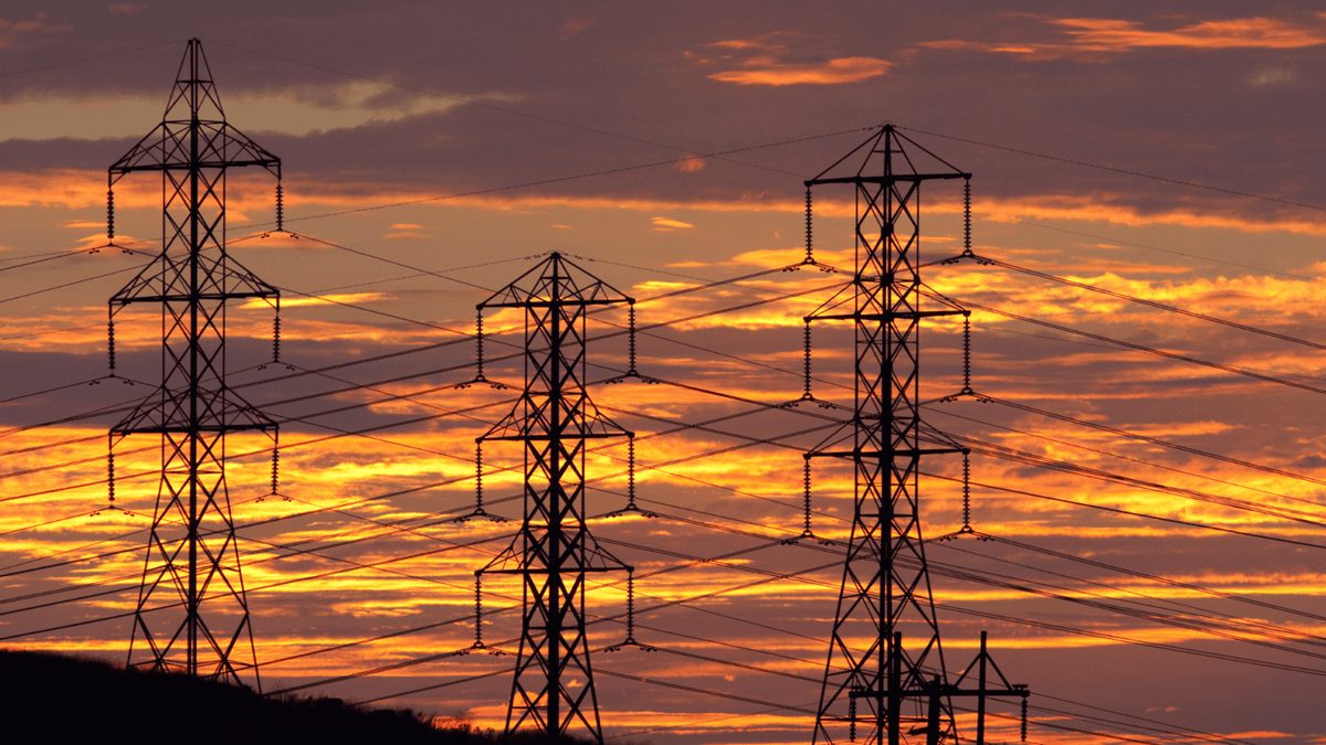 Electricity transmission towers silhouetted at sunset