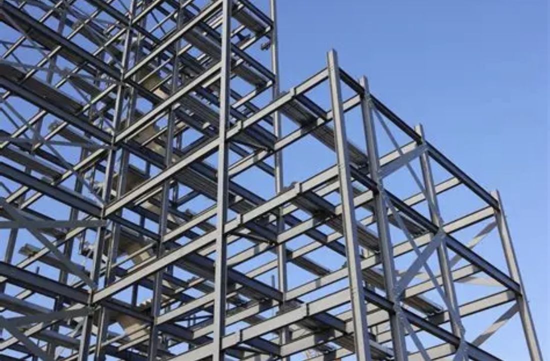 Structural steel frame under construction against a blue sky