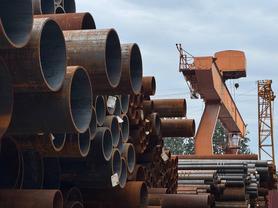 Stacked steel pipes at a yard, representing OCTG and threading stock