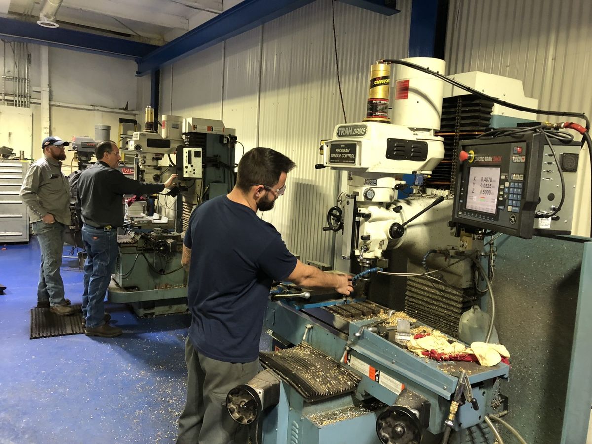 Machinists operating a CNC milling machine in a machine shop