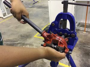 Technician using a manual pipe threading tool
