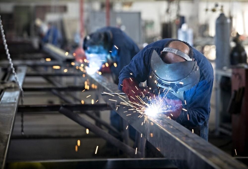 Welders fabricating steel structures with visible sparks