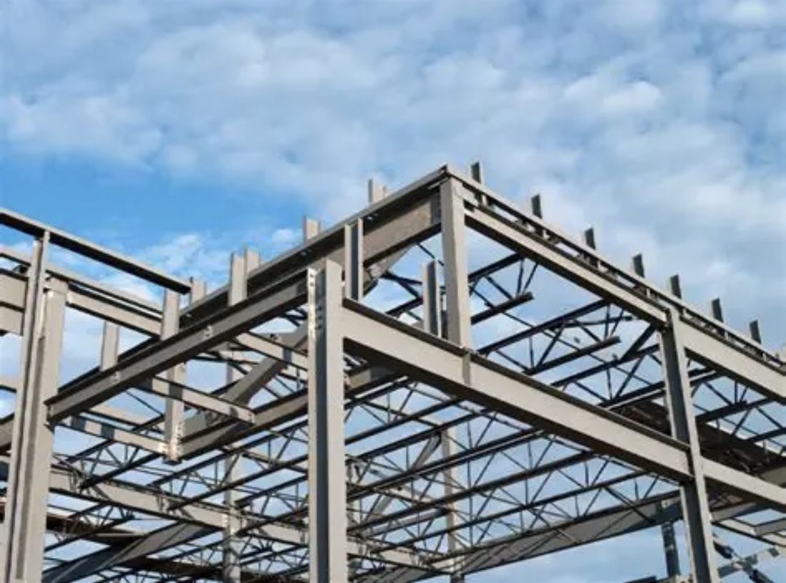 Structural steel frame apex against a cloudy sky
