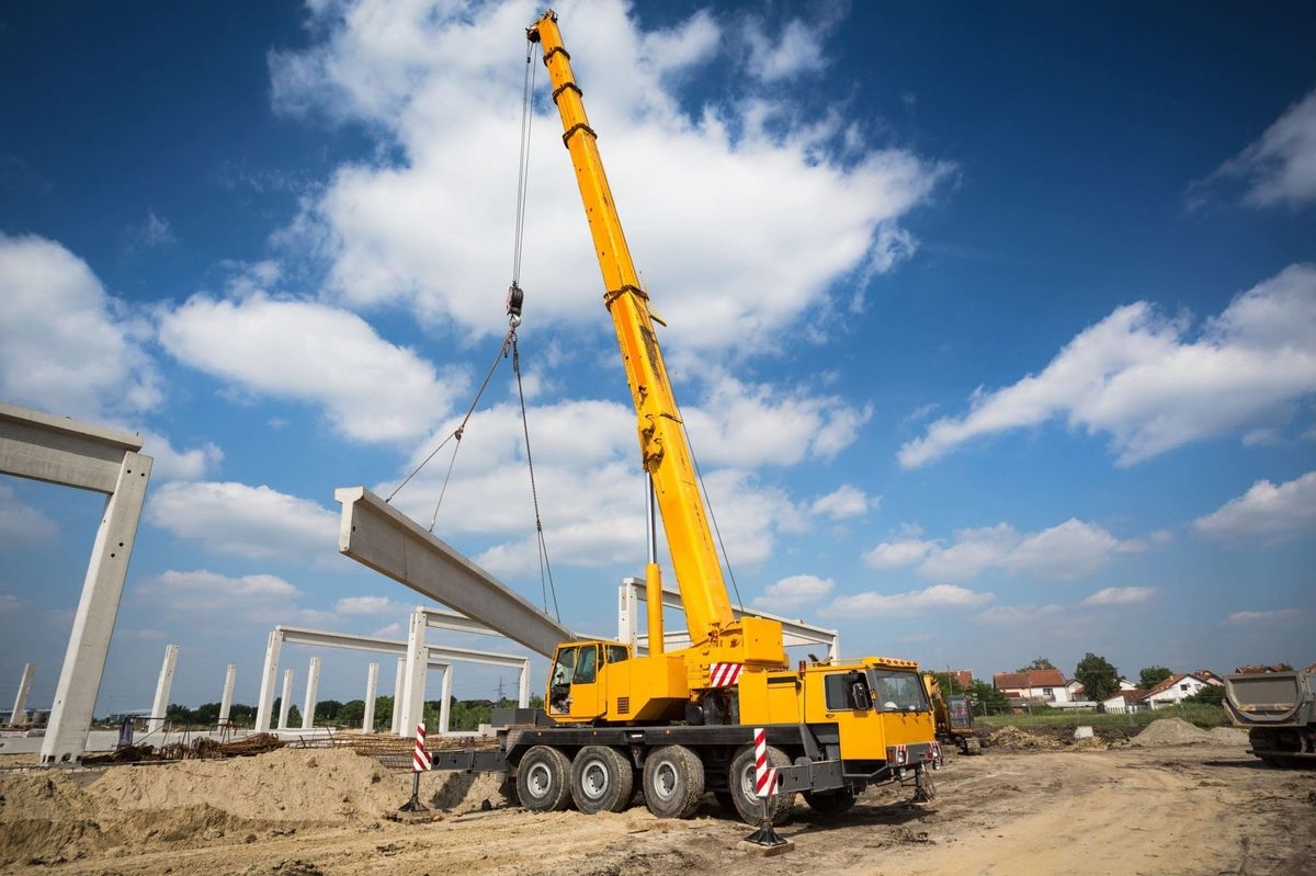 Mobile crane lifting a precast concrete beam on a construction site